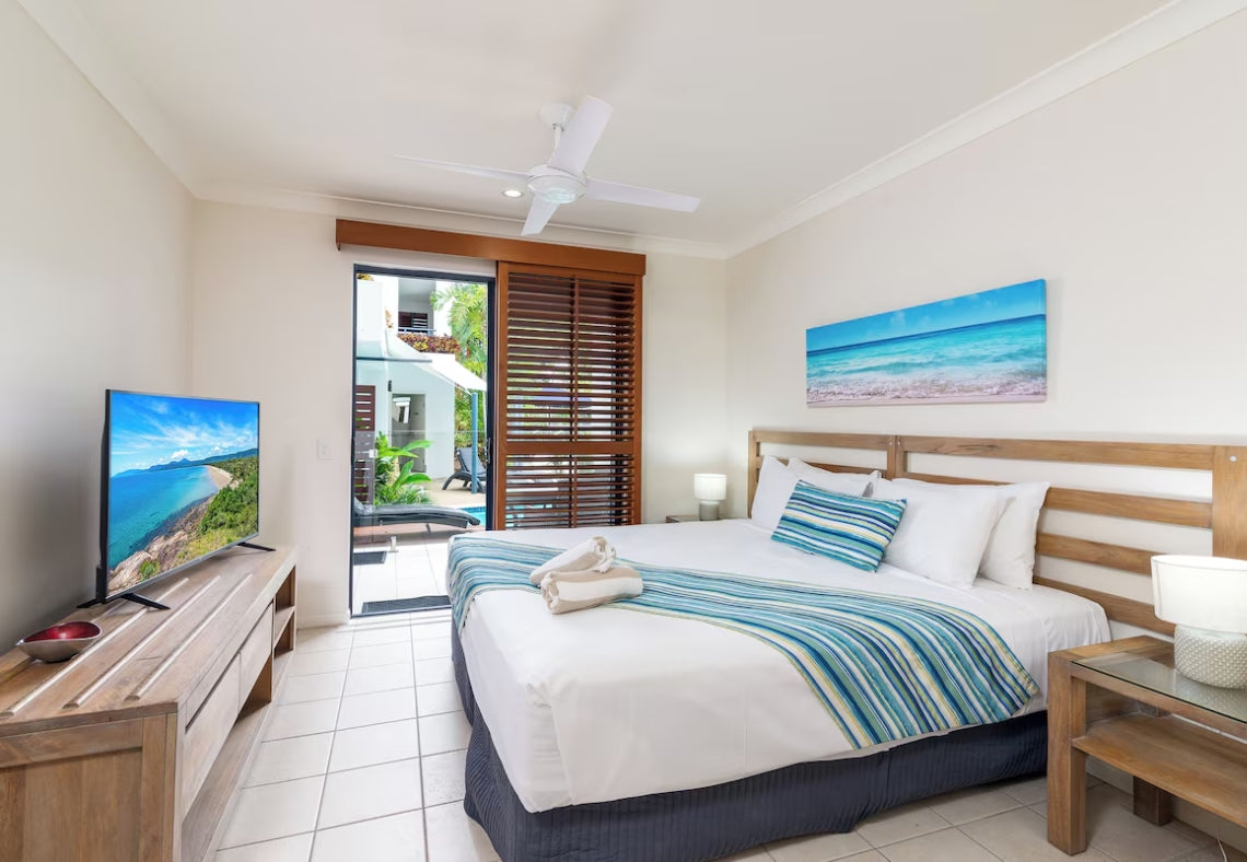 Luxury Studio apartment accommodation at Meridian Port Douglas with a bed, TV, and view of a pool and beach.