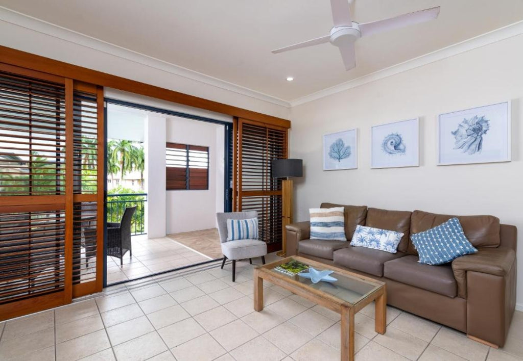 Meridian Port Douglas Resort Living room with brown sofa, coffee table, and sliding glass doors leading to a patio.