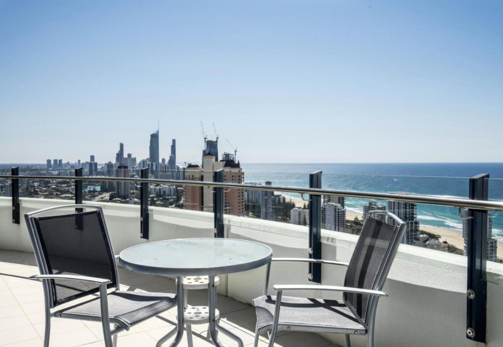 Terrace with table and chairs overlooking city and ocean.