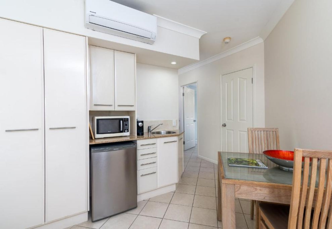 Small kitchen with white cabinets, stainless steel appliances, and a dining table.