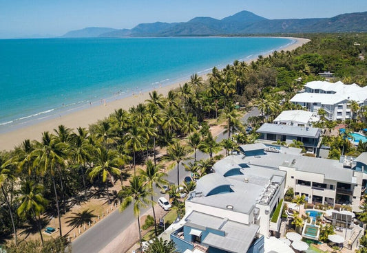 Aerial view of a coastal area with resorts and hotels, palm trees, and port douglas four mile beach.