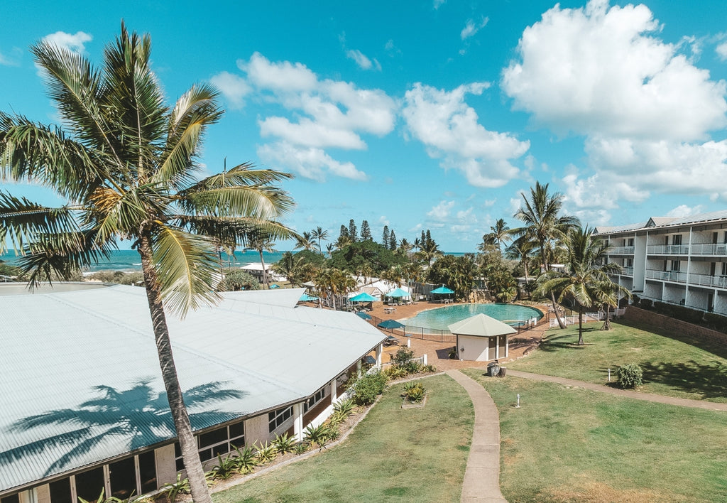 Aerial view of a tropical resort with palm trees, buildings, and a pool.